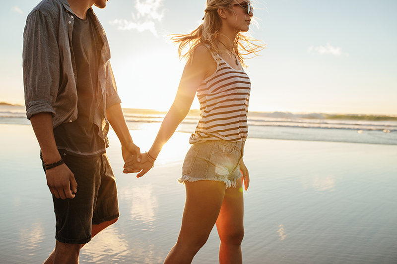 young couple holding hands walking on the beach